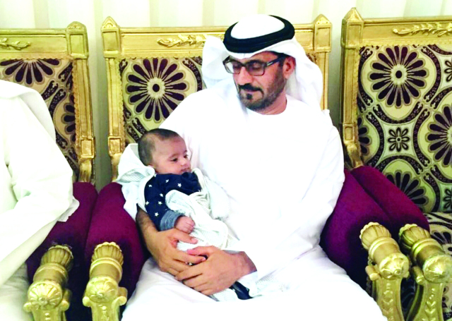 "■ حسين الحمادي يحمل طفلاً لأحد شهداء رأس الخيمة خلال تقديمه العزاء | البيان"