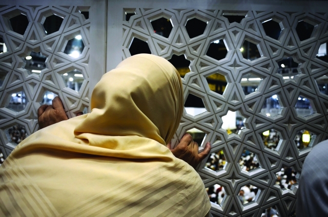 "■ حاجة تستطلع معالم الكعبة من بين الثقوب | أ.ف.ب"