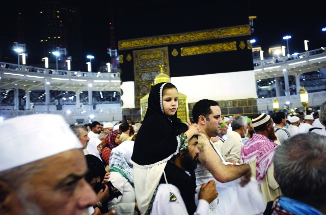 "■ حاج يحمل طفلته أثناء الطواف | أ.ف.ب"