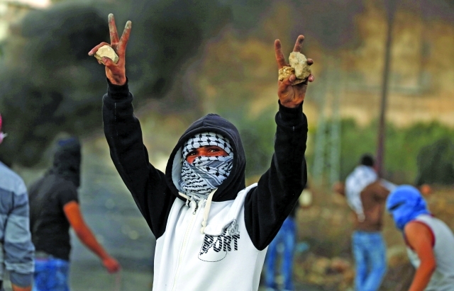"■ شاب فلسطيني يرفع إشارة النصر خلال الاشتباكات | أ.ف.ب"