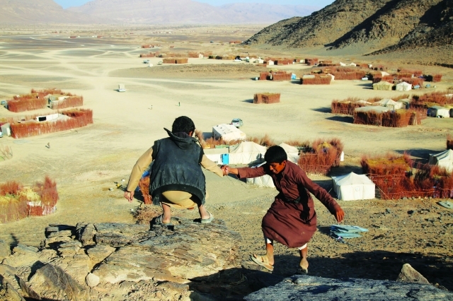 "■ طفلان نازحان يلهوان أعلى تلة تقع أسفلها منازلهم المبنية من أغصان الأشجار في مأرب | البيان"