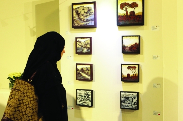 "■ إحدى الزائرات تتأمل منمنمات بصرية تدخل في أجواء القصائد المغناة في المعرض"
