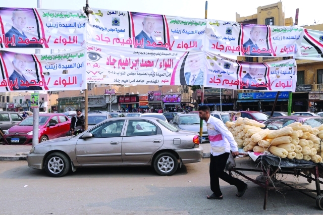 "■ بائع متجول يدفع عربة تحت لافتات الدعاية الانتخابية في القاهرة | إي.بي.إيه"