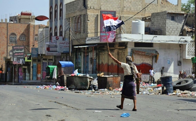 "مقاتل من المقاومة يرفع علم اليمن على جبهة القتال في مدينة تعز | تصوير: أحمد الباشا"