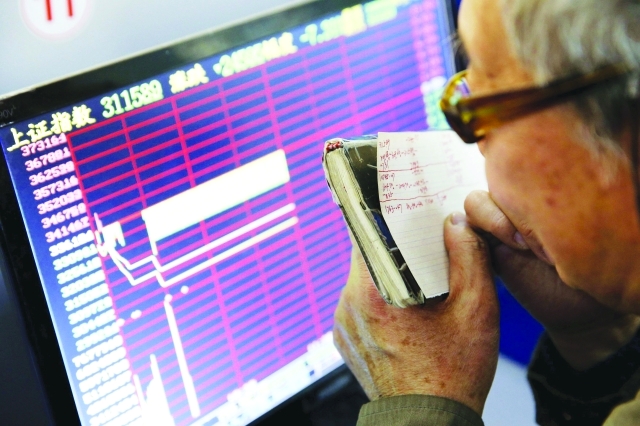 "مستثمر صيني يتابع معلومات الأوراق المالية في بورصة شنغهاي أمس - رويترز"