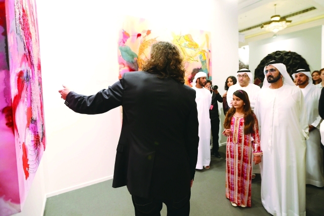 "■.. ويستمع إلى شرح من أحد الفنانين عن لوحة في المعرض"