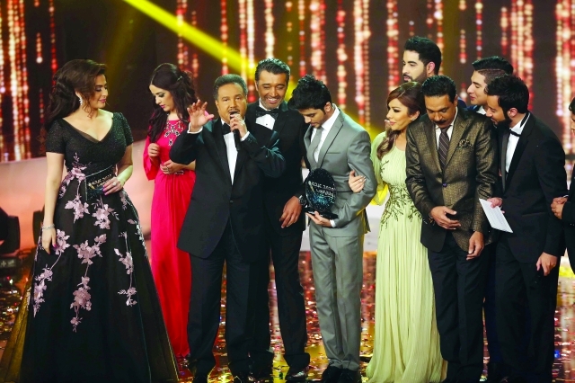 "■ محمد عبده يتوسط أسامة محبوب الفائز بلقب البرنامج ولجنة التحكيم ومقدمي البرنامج  |  من المصدر"