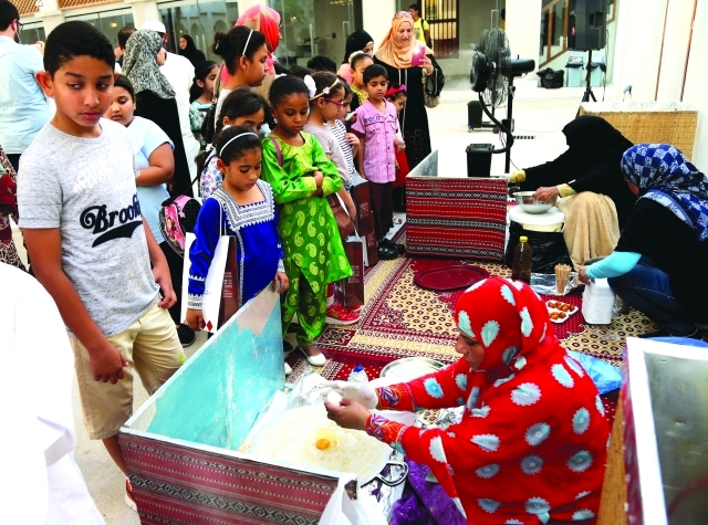 "■ صغار يتابعون فعاليات الأكلات الشعبية ومنها اللقيمات وخبز الرقاق  |  تصوير: محمود الخطيب"