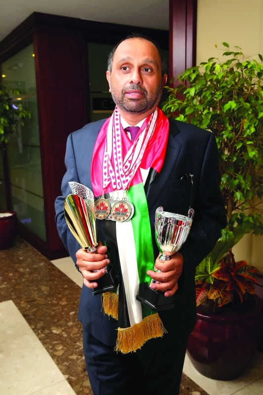 "■ أحمد مجان يحمل الميداليات والكأس والدرع"