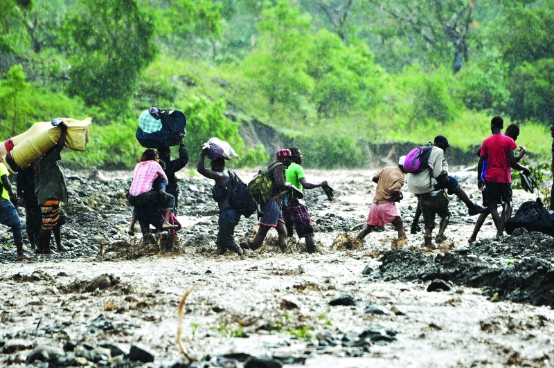 "TOPSHOT - Haitian people cross the river La Digue in Petit Goave where the bridge collapsed during the rains of the Hurricane Matthew, southwest of Port-au-Prince, October 5, 2016. Haiti and the eastern tip of Cuba -- blasted by Matthew on October 4, 2016 -- began the messy and probably grim task of assessing the storm's toll. Matthew hit them as a Category Four hurricane but has since been downgraded to three, on a scale of five, by the US National Hurricane Center. / AFP / HECTOR RETAMAL"