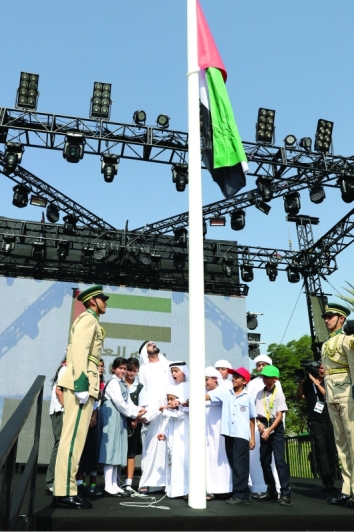 "محمد بن راشد والجليلة بنت محمد خلال رفع علم الوطن على السارية"