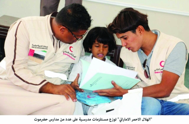 "موظفان من «الهلال الأحمر» يشرحان لتلميذة عن محتويات الحقيبة المدرسية| وام"
