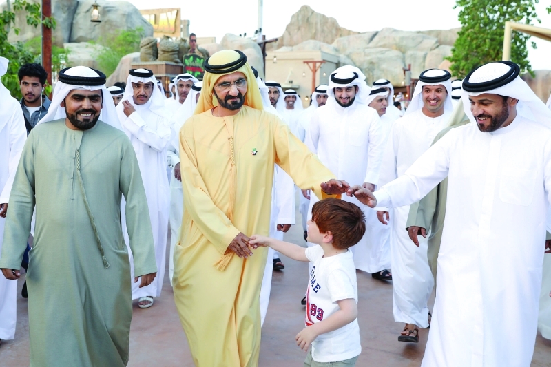 "■ محمد بن راشد يصافح أحد الأطفال بحضور أحمد بن محمد وأحمد الزعابي"