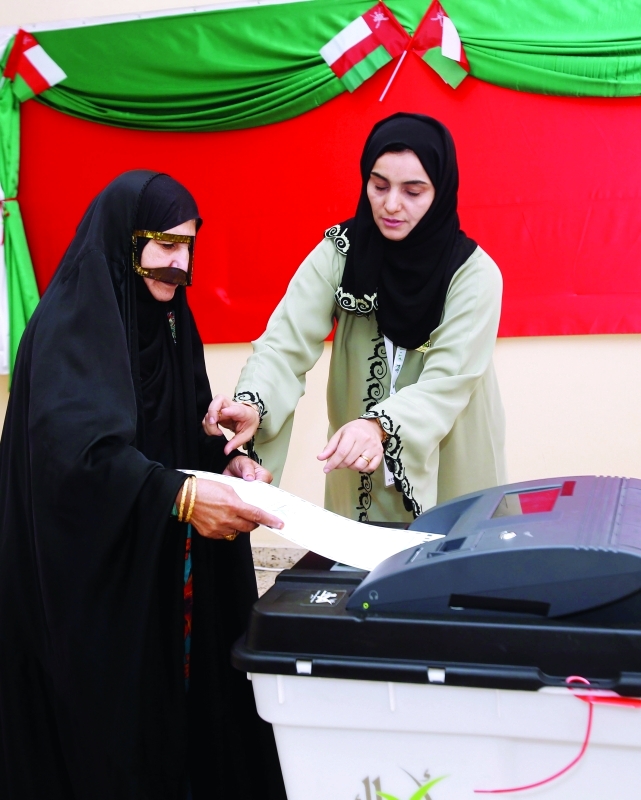 "■ امرأة عمانية تدلي بصوتها في أحد مراكز الاقتراع | أ.ف.ب"