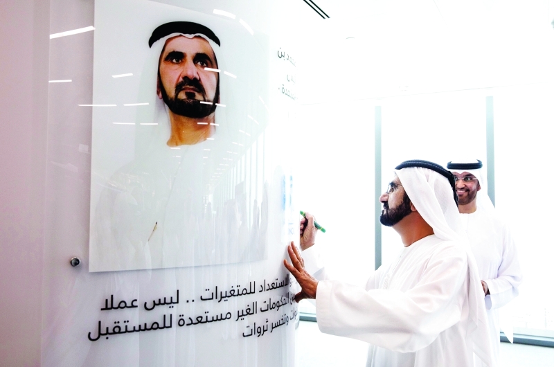 "■ محمد بن راشد خلال توقيعه على لوحة تحمل صورة سموه"