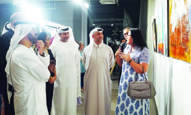 "■ ياسر القرقاوي وخليل عبدالواحد والحضور يستمعون إلى شرح إحدى الفنانات المشاركات | تصوير: حصة إسماعيل"