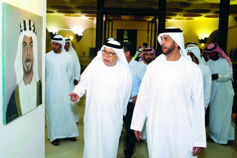 "■ خليفة بن محمد يستمع إلى شرح من حبيب الصايغ عن اللوحات المشاركة في المعرض | تصوير: مجدي اسكندر"