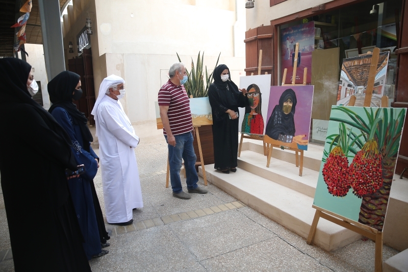 "عزة الكتبي تتحدث عن لوحات معرضها أمام عدد من الزائرين | تصوير: إبراهيم صادق"