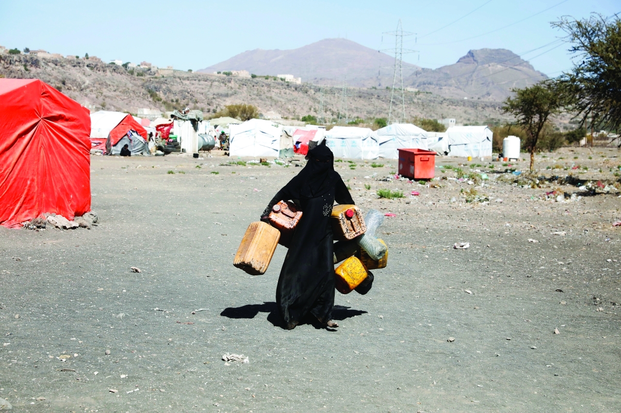 "يمنية نازحة تحمل أوعية فارغة لتعبئتها بالمياه في مخيم للنازحين | إي.بي.إيه"