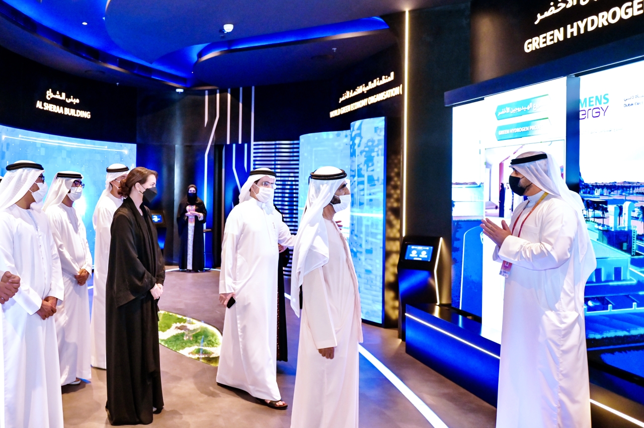 "محمد بن راشد مستمعاً إلى شرح في جناح كهرباء دبي بحضور مريم المهيري وسعيد الطاير"