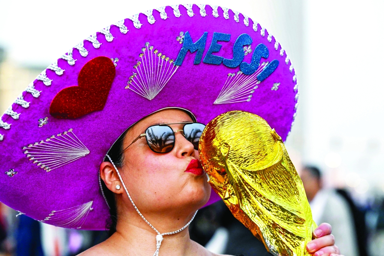 "TOPSHOT - A supporter poses with a replica of the FIFA World Cup Trophy before the Qatar 2022 World Cup football final match between Argentina and France at Lusail Stadium, north of Doha, on December 18, 2022. (Photo by INA FASSBENDER / AFP)"