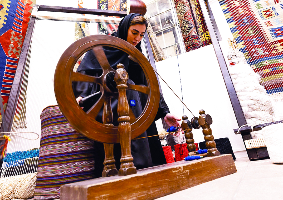 "إلهام خير الله خلال حياكتها السجاد في ورشتها بحي الفهيدي | تصوير : سالم خميس"