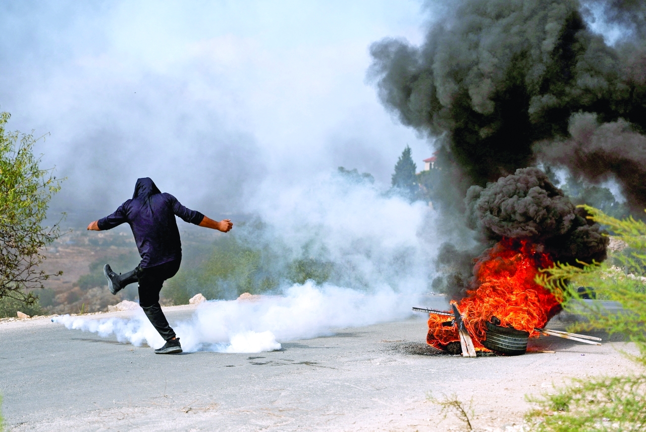 "A Palestinian protestor kicks a tear-gas canister during clashes with the Israeli forces, near Tulkarm, in the Israeli-occupied West Bank, October 5, 2023. REUTERS/Raneen Sawafta TPX IMAGES OF THE DAY"