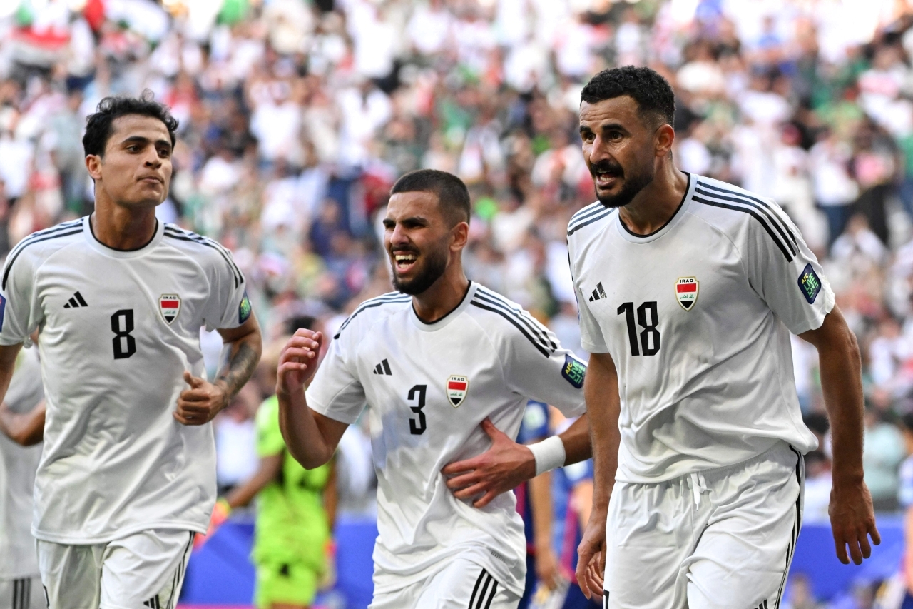 "أيمن حسين يحتفل مع لاعبي العراق بهدفيه في مرمى اليابان | أ ف ب"