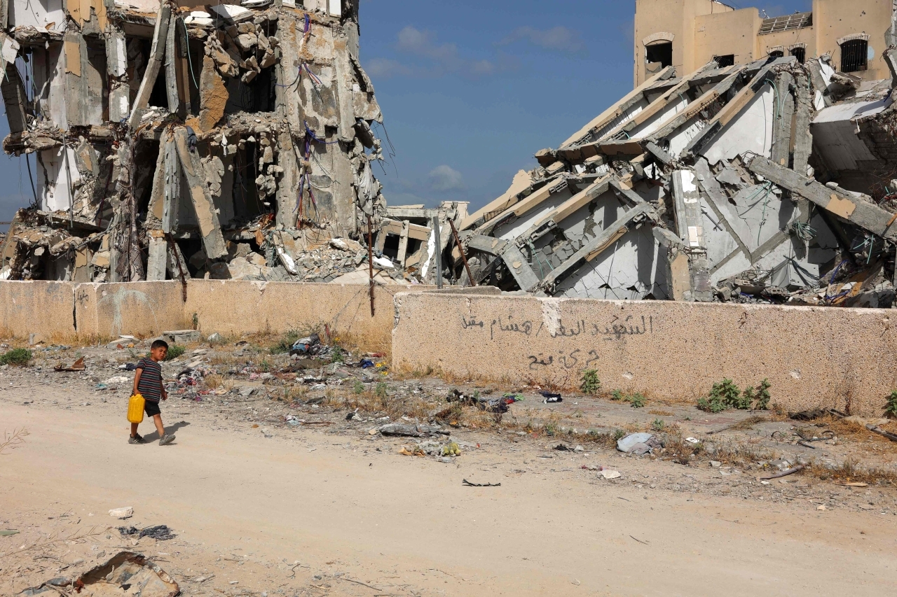 "صبي فلسطيني يحمل علبة مياه وسط الدمار في بيت لاهيا| أ.ف.ب"