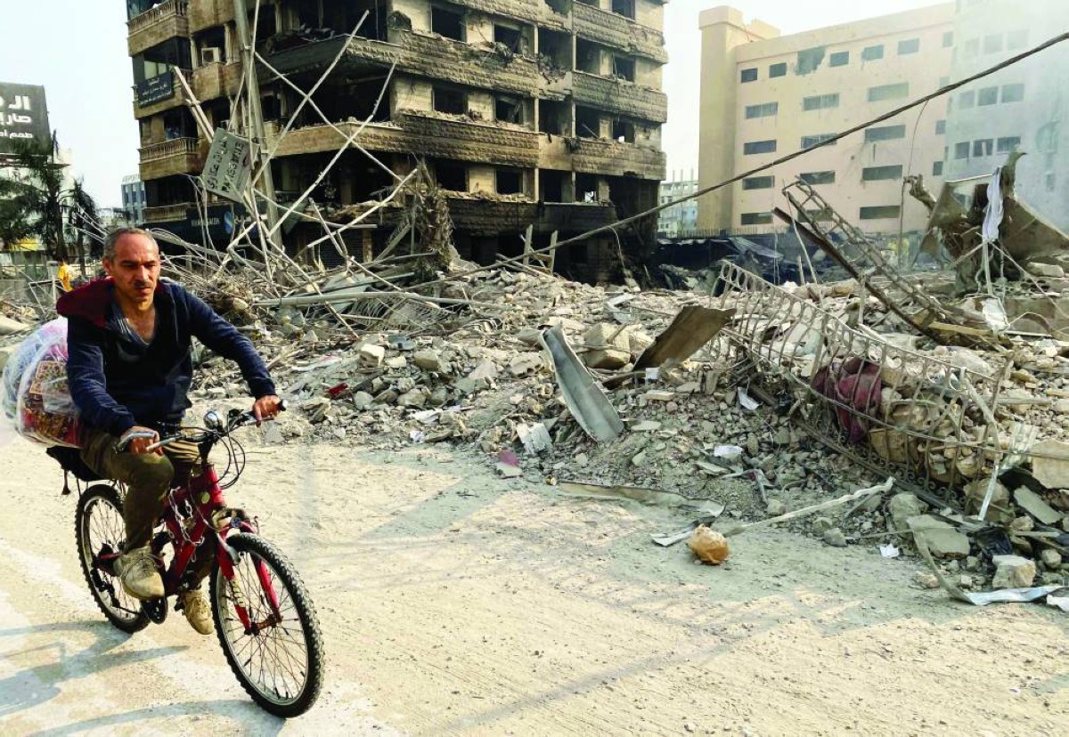 رجل يركب دراجة هوائية أمام مبنى مدمر في أحد أحياء الضاحية الجنوبية لبيروت