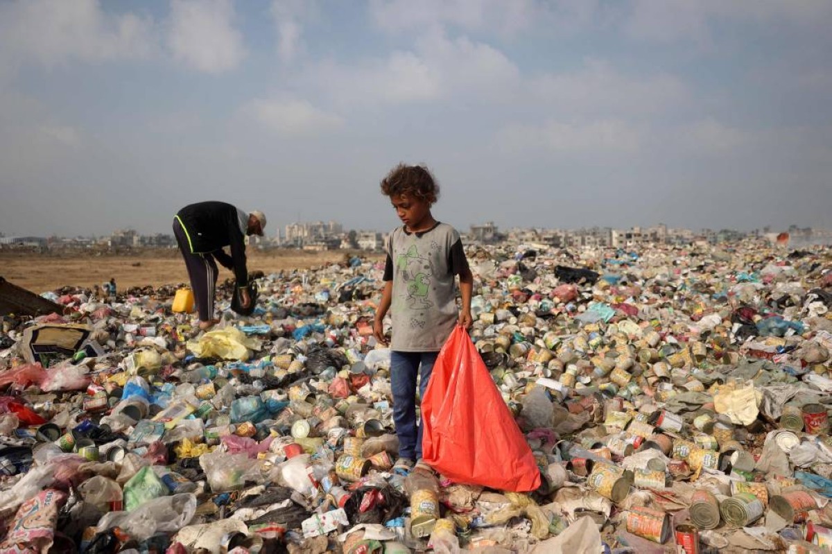 طفل فلسطيني نازح ورجل ينقبان في القمامة بمخيم البريج للاجئين