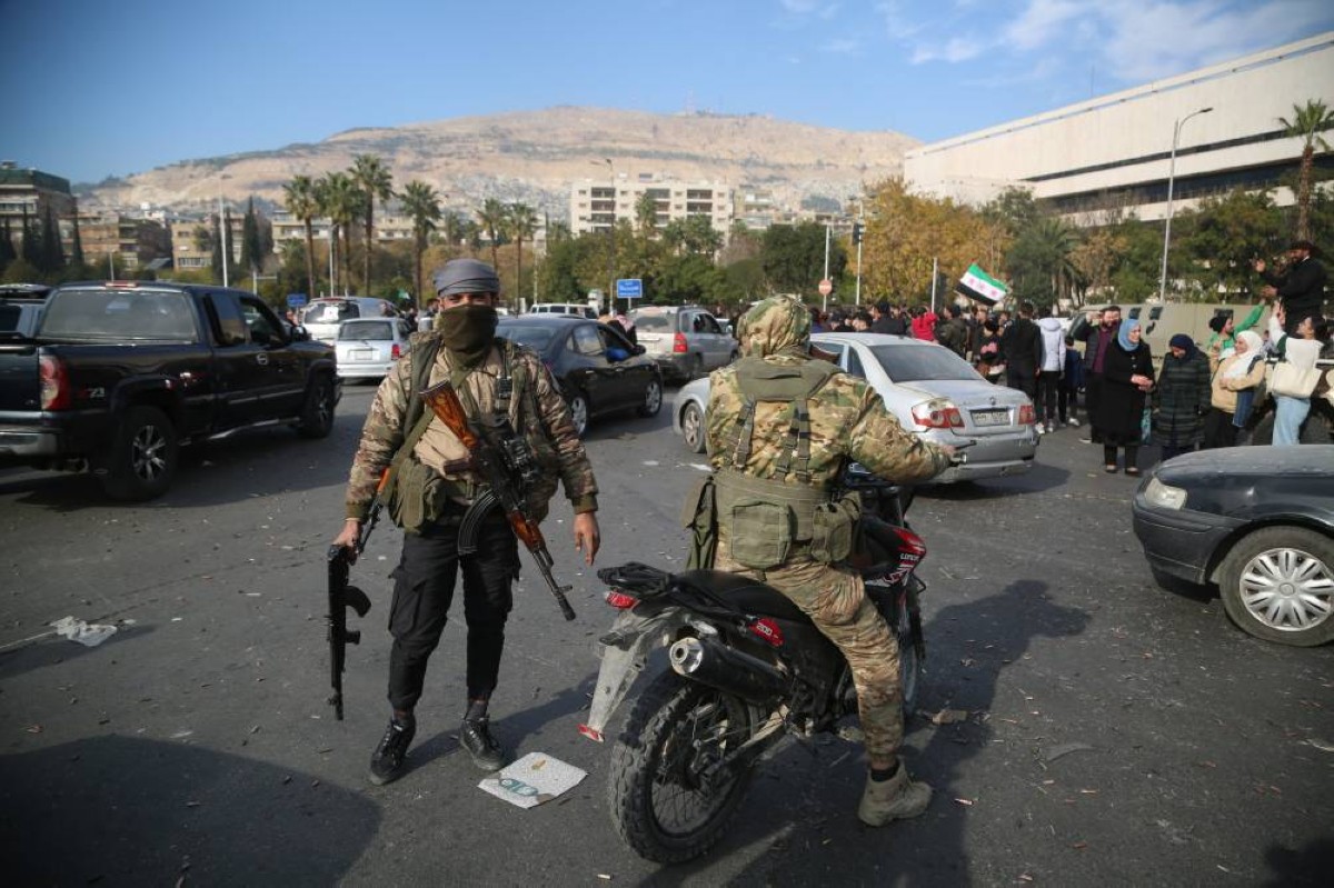 مسلّحان وحشد من الأشخاص في دمشق بعد سقوط النظام