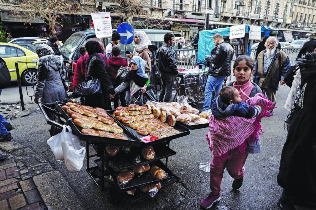 سوريون يتسوقون أمام كشك بائع متجول في وسط مدينة دمشق 