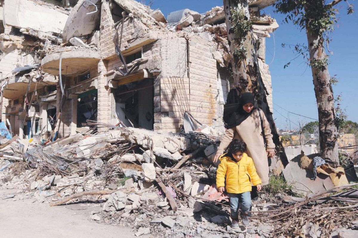 امرأة مع ابنها بين الأنقاض عند بناية مدمرة بقرية الطيبة جنوبي لبنان |