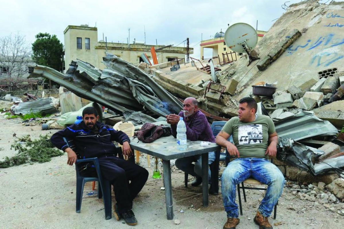 لبنانيون يجلسون أمام منزلهم المدمر في قرية الوزاني بجنوب لبنان