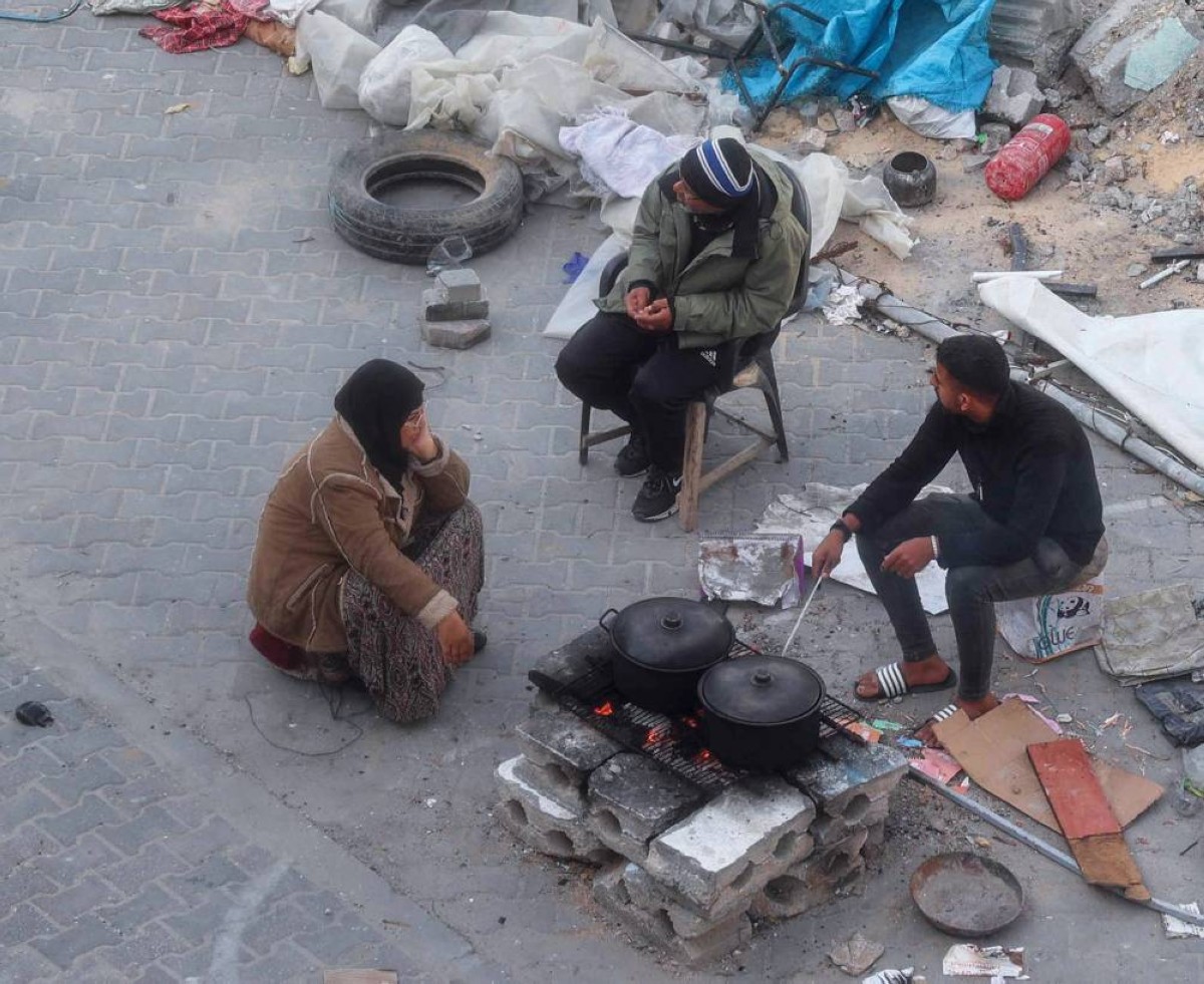 نازحون في مخيم البريج للاجئين يعدون وجبة الإفطار في الشارع