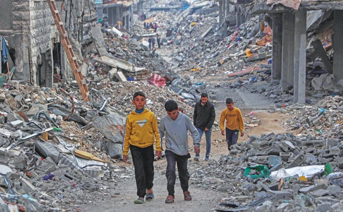 أطفال فلسطينيون يسيرون بين المنازل المدمرة في بيت لاهيا شمال غزة