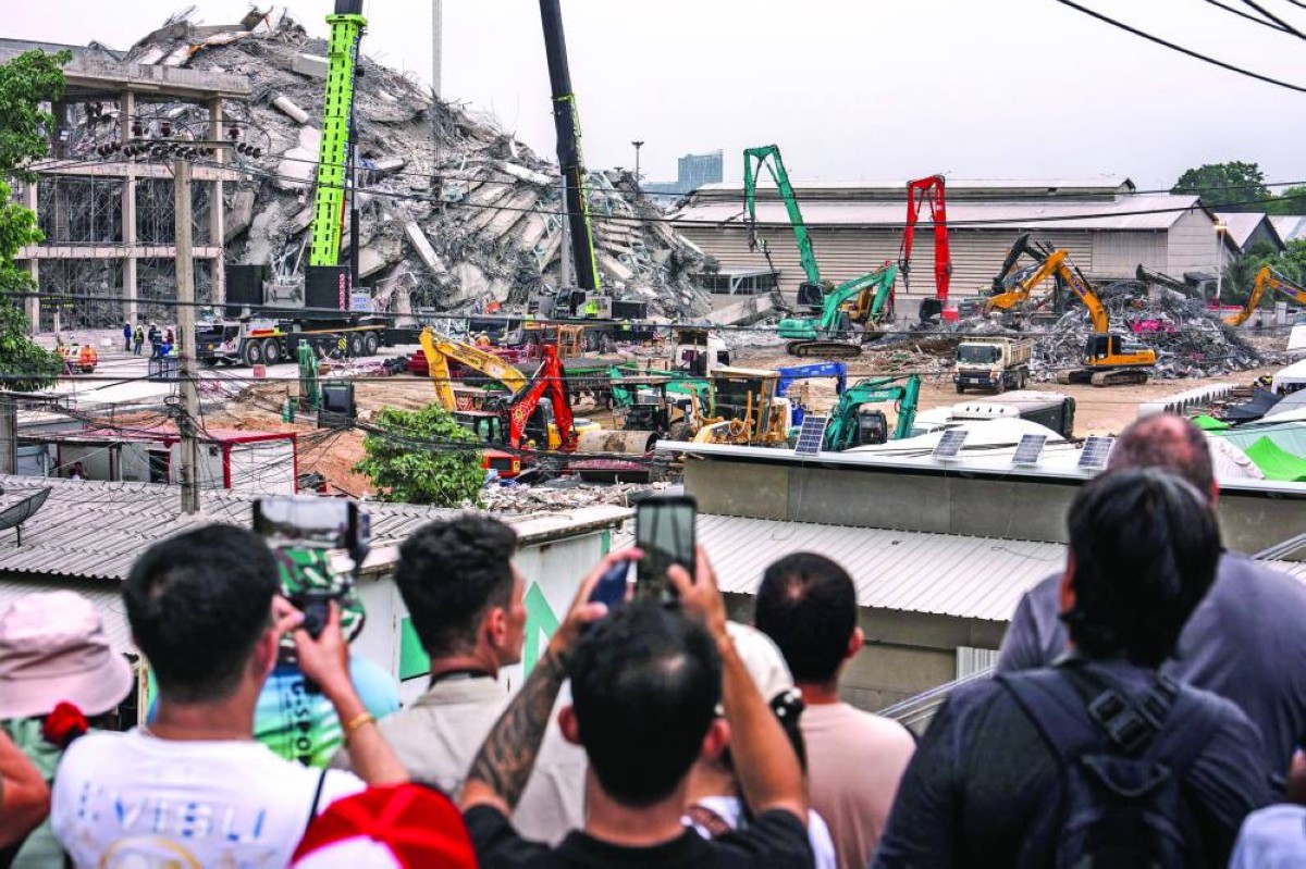 شبان يتابعون عمليات إزالة الأنقاض من موقع منهار في بانكوك