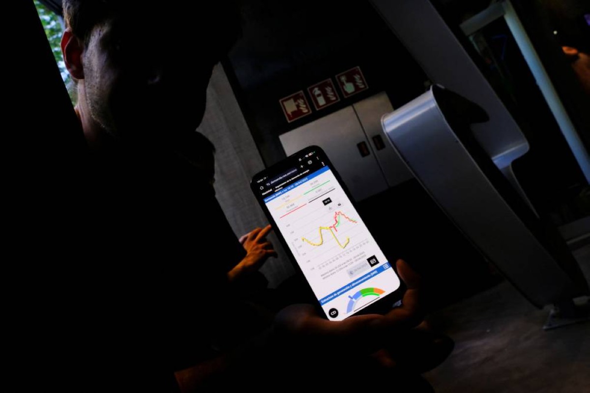 يعرض كارلوس سيكو، 24 عامًا، على هاتفه رسمًا بيانيًا يظهر انخفاضًا حادًا في الطلب على الكهرباء في إسبانيا