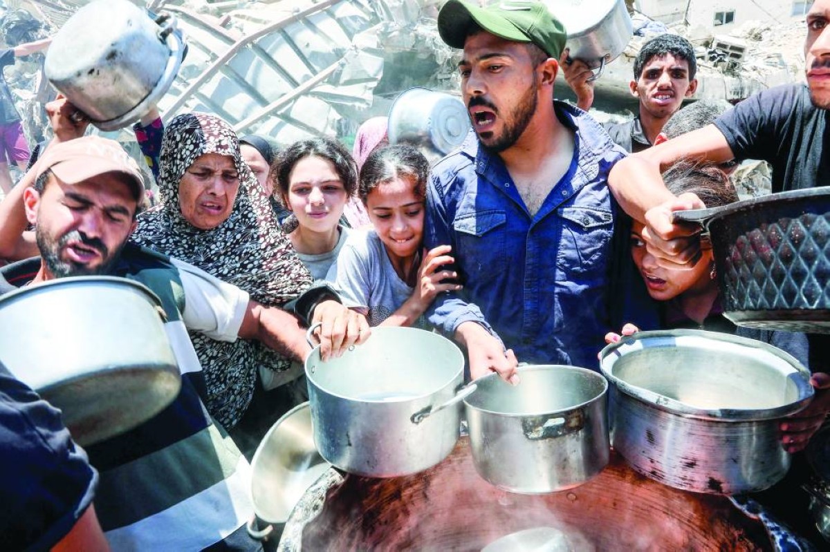 فلسطينيون يحاولون الحصول على الطعام من مطبخ خيري في حي الرمال بغزة