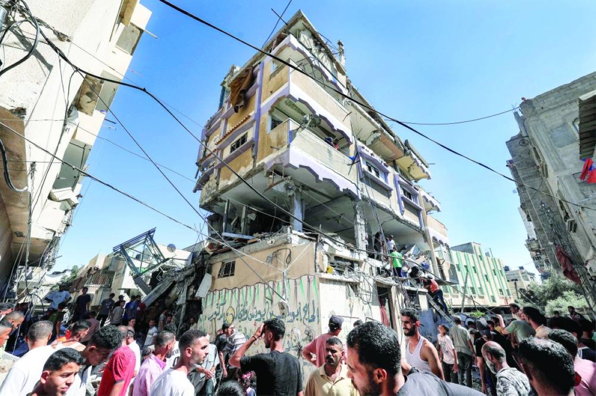 فلسطينيون قرب بناية آيلة للسقوط بعد قصف إسرائيلي على مخيم النصيرات