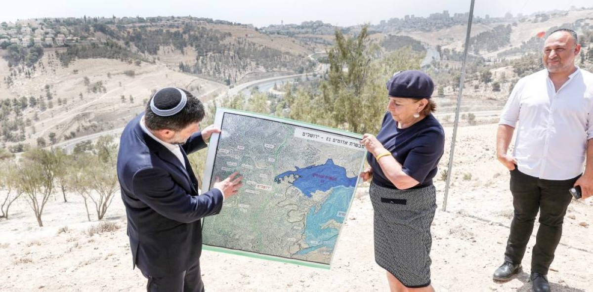 بتسلئيل سموتريتش وامرأة في مستوطنة «معاليه أدوميم» يحملان خريطة للمخطط الاستيطاني 