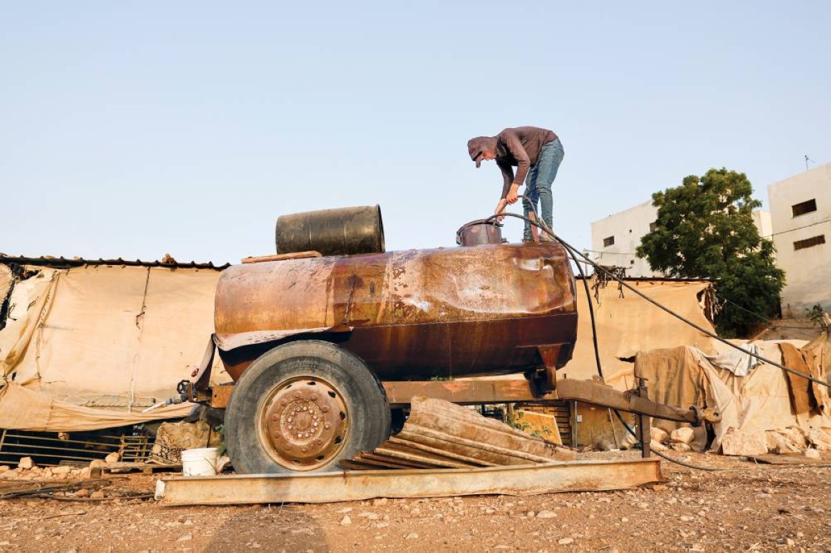 فلسطيني يملأ خزان مياه في قرية بردلة بالضفة الغربية


