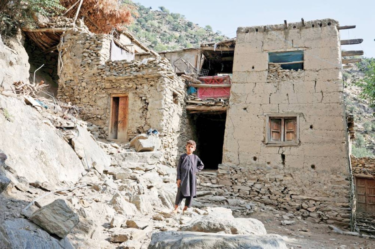 طفل أفغاني يقف أمام بيت بسيط متصدع جراء الزلزال 