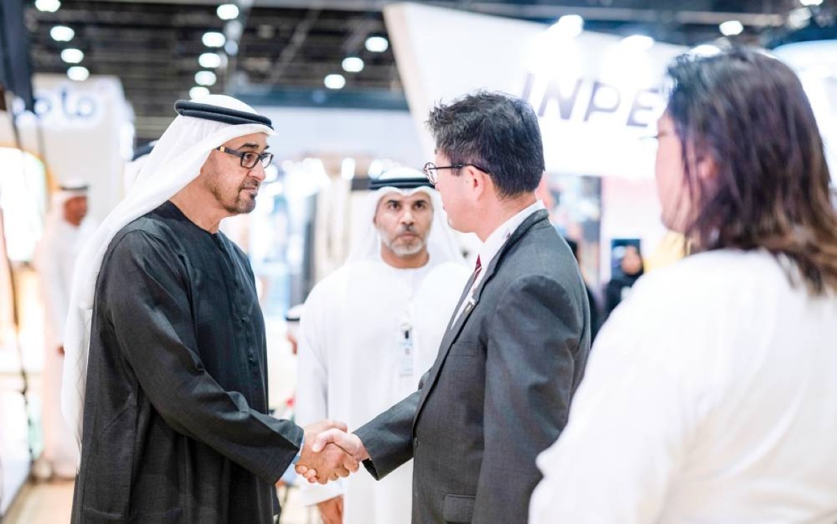  محمد بن زايد مصافحاً أحد المشاركين في المعرض بحضور حميد الظاهري 