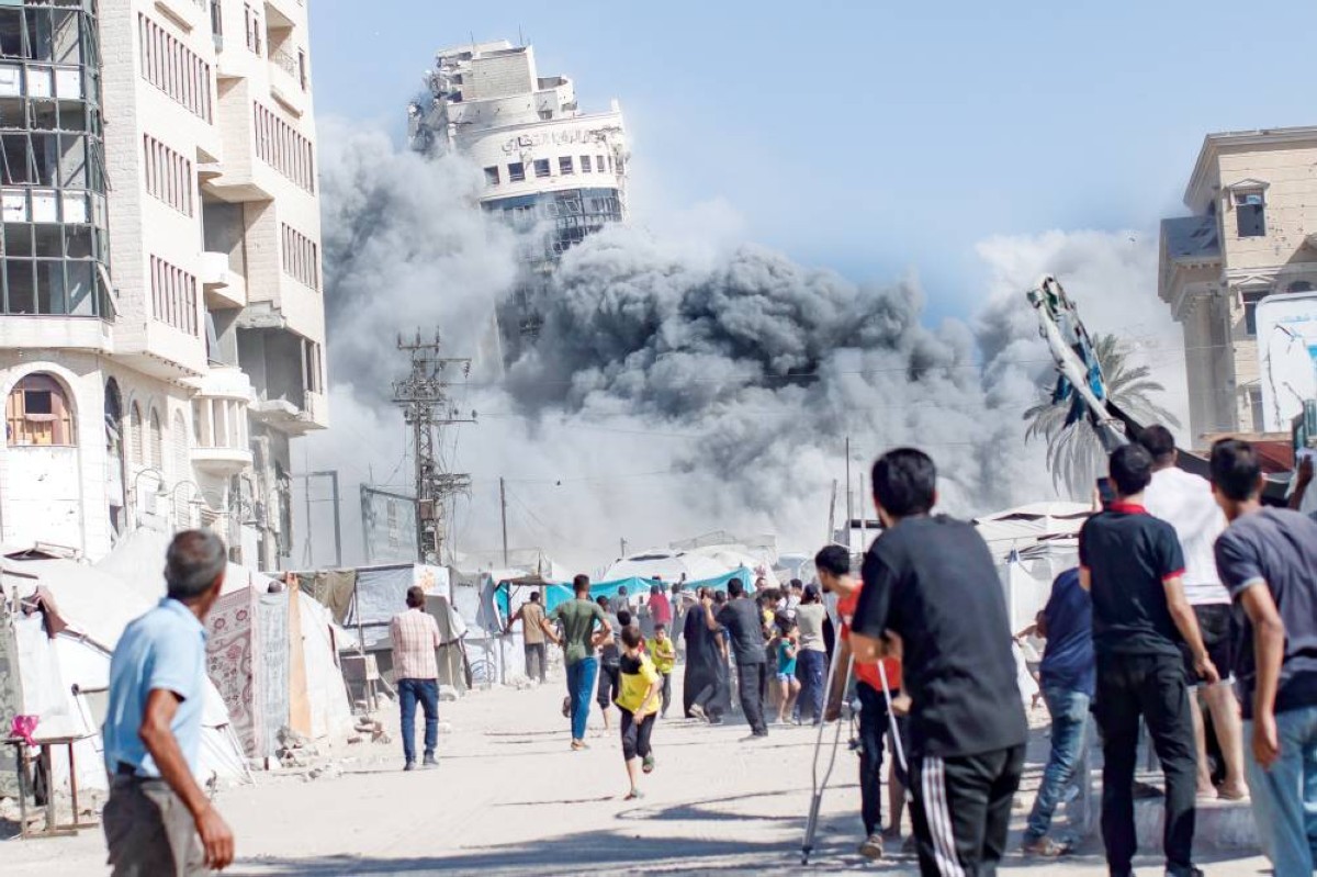 فلسطينيون يراقبون تفجير الطائرات الإسرائيلية لبرج سكني في مدينة غزة 