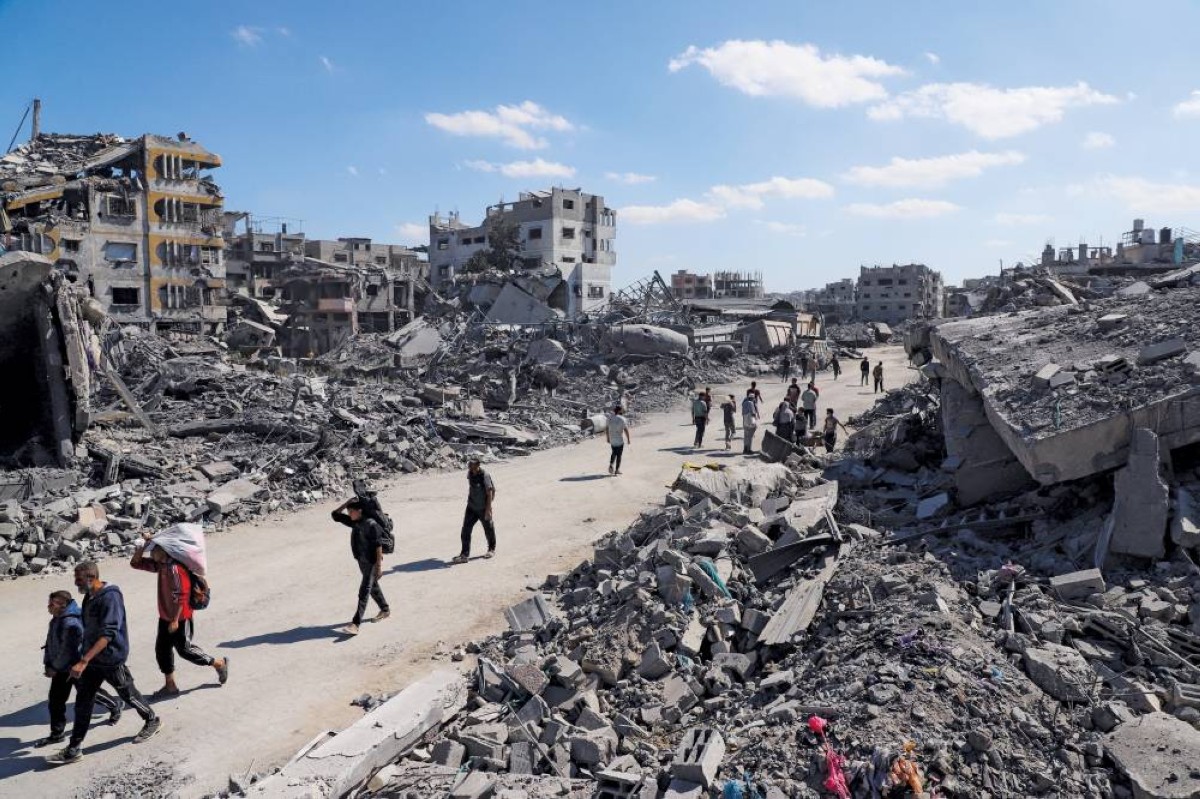 فلسطينيون يسيرون بين أنقاض المباني المدمرة إثر إعلان وقف إطلاق النار في غزة 

