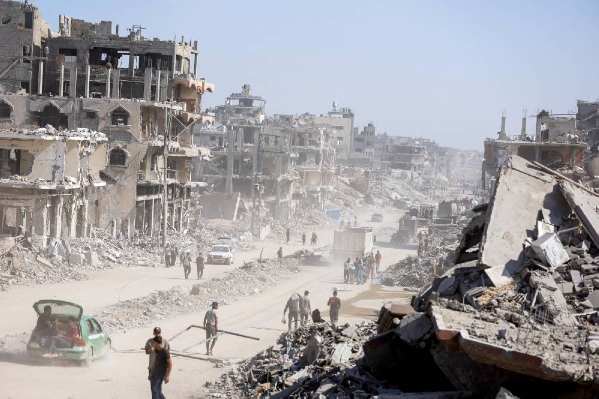 فلسطينيون يسيرون بين أنقاض الدمار الهائل الذي خلّفته الحرب الإسرائيلية على مدينة غزة