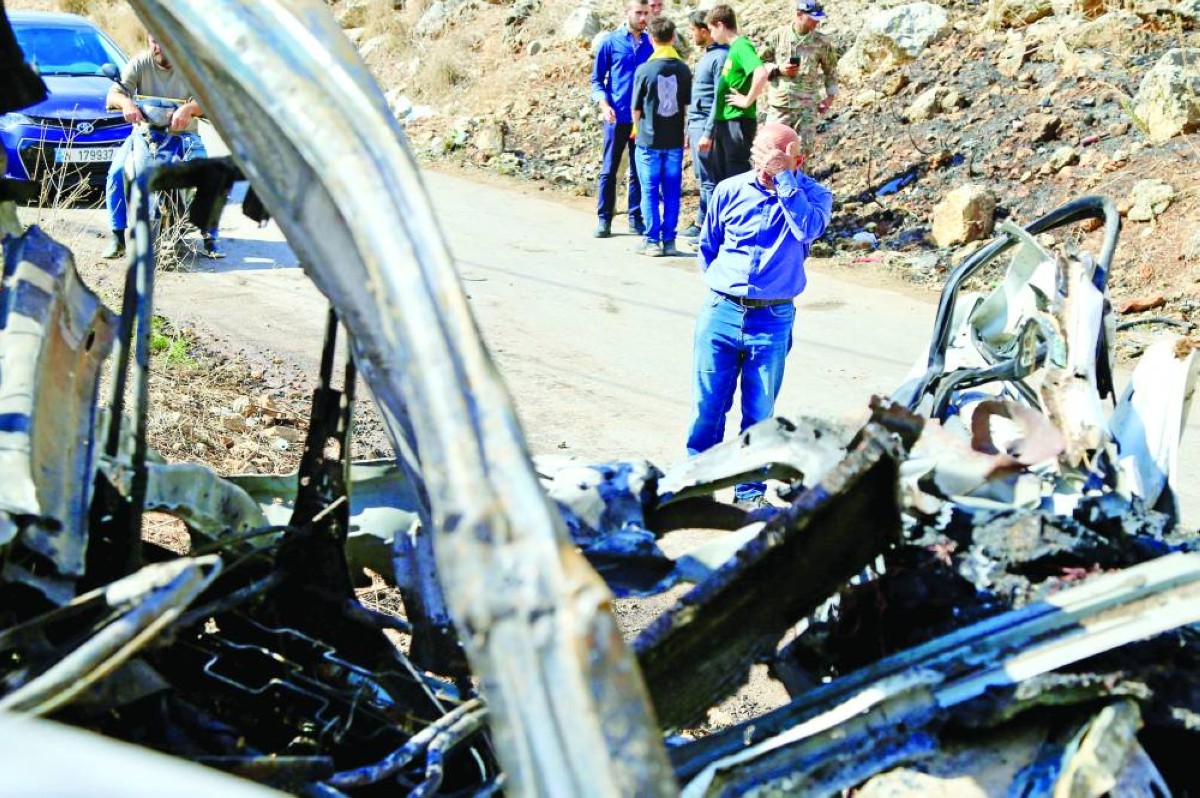 لبنانيون يتفقدون حطام سيارة استهدفتها مسيّرة إسرائيلية في قرية حاروف بالنبطية