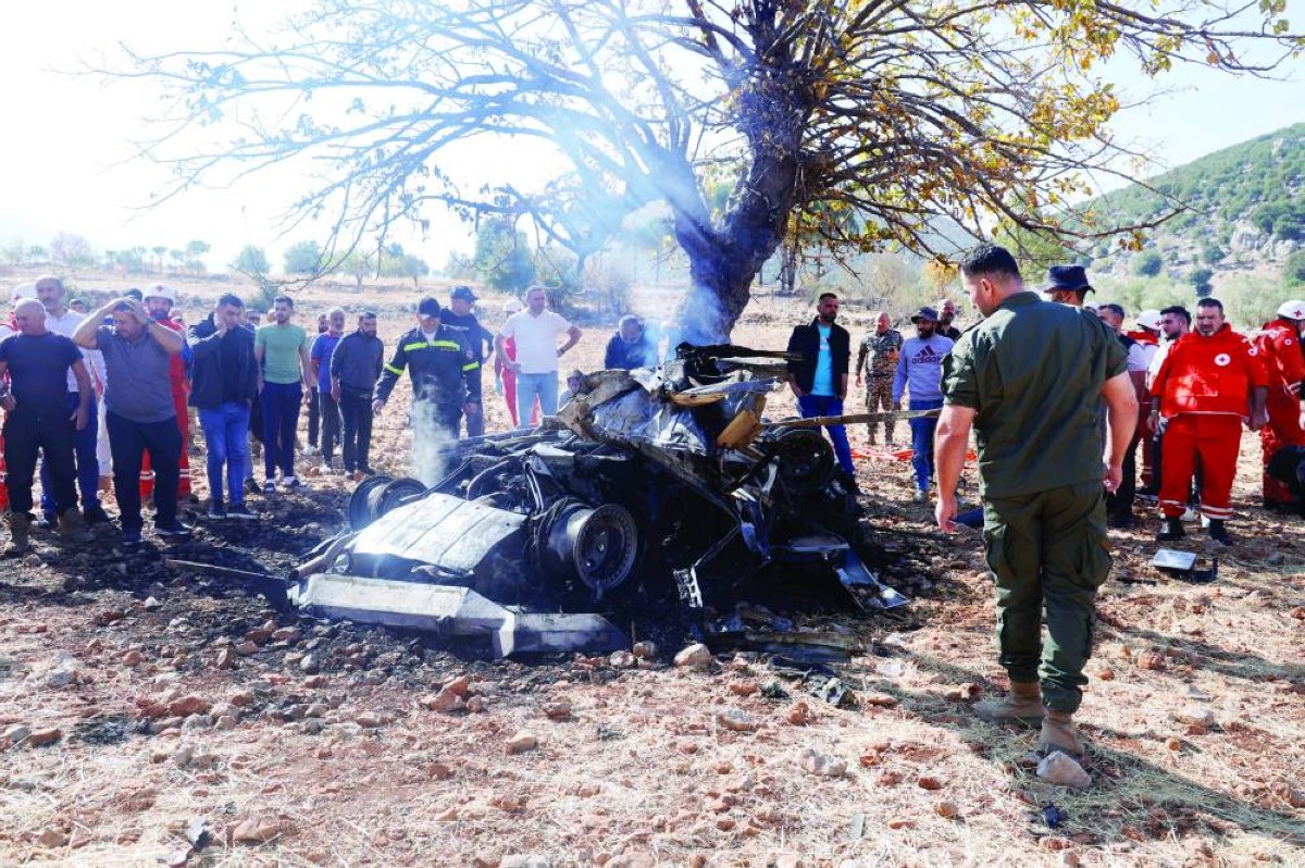 لبنانيون يتجمعون حول بقايا مركبة احترقت بالكامل إثر غارة إسرائيلية على بلدة شبعا جنوب لبنان 